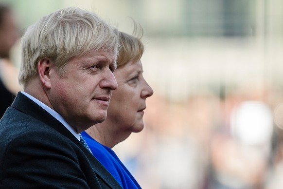epa07784817 German Chancellor Angela Merkel (R) and British Prime Minister Boris Johnson sit next to each other during a ceremony with military honors at the Chancellery in Berlin, Germany, 21 August  ...