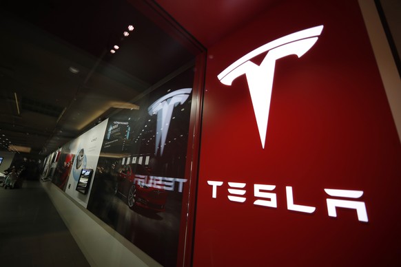 FILE- In this Feb. 9, 2019, file photo, a sign bearing the company logo is displayed outside a Tesla store in Cherry Creek Mall in Denver. The U.S. governmentÄôs highway safety agency says itÄôs gat ...