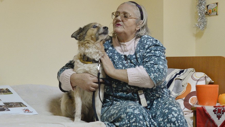 FILE - In this Wednesday, Dec. 10, 2014 file photo, Elena Calugaru, 60, pets Tibi, a 11 year old stray dog, in Bucharest, Romania. Elena Calugaru, 60, calls Tibi “my boy, my love!” and her eyes well u ...