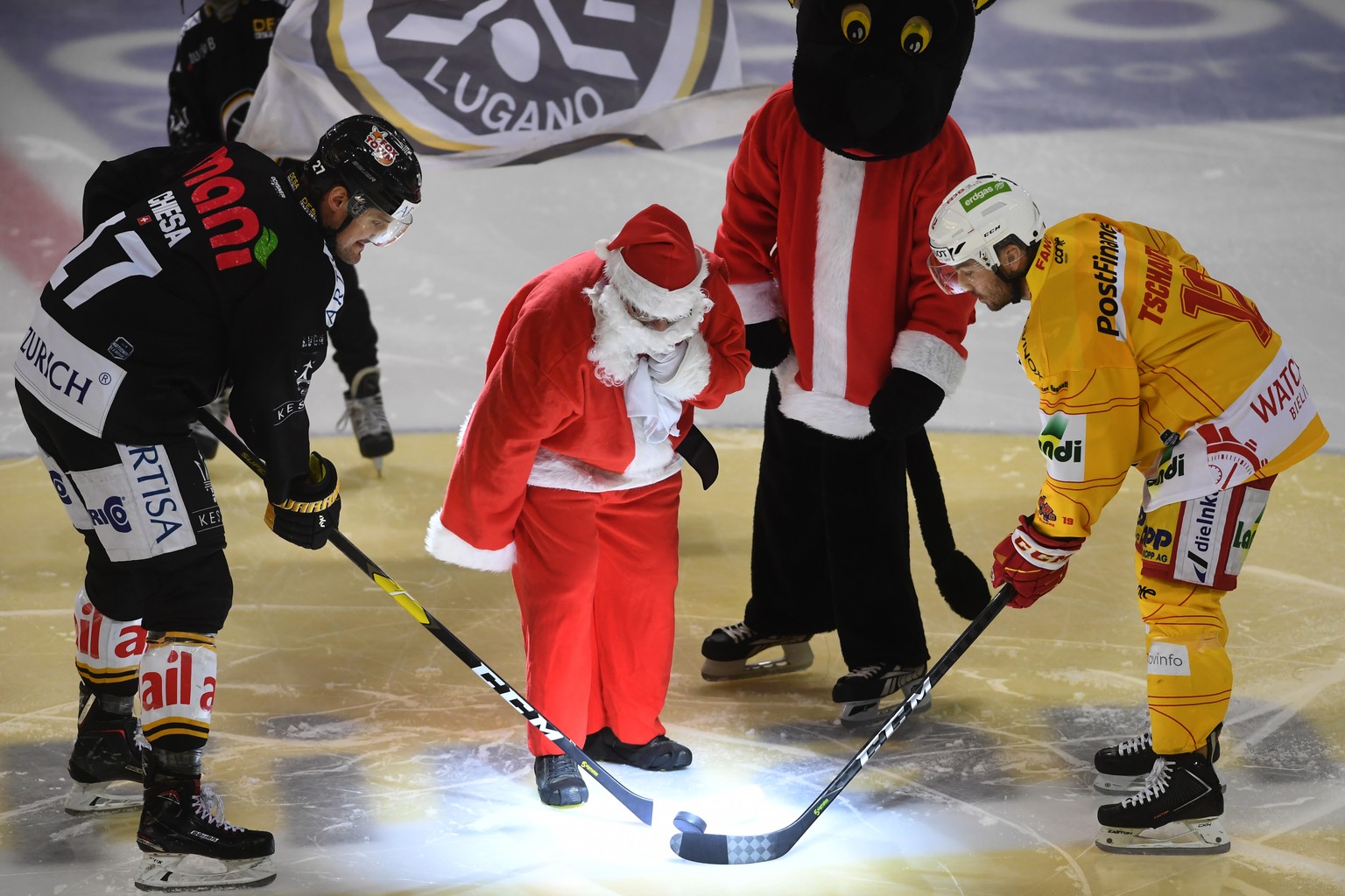 Lugano&#039;s player Alessandro Chiesa, left, during the face off with Santa Claus, center, and Biel&#039;s player Mathieu Tschantre, right, during the preliminary round game of National League Swiss  ...