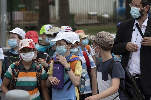 Israeli school children wear face masks to help prevent the spread of the coronavirus as they walk in Tel Aviv, Israel, Monday, July 6, 2020. (AP Photo/Sebastian Scheiner)