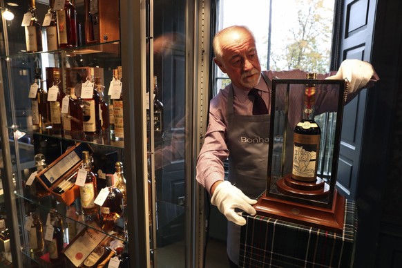 Danny McIlwraith from Bonhams auction house holds bottle of the world&#039;s rarest and most valuable whisky, The Macallan Valerio Adami, at the Bonhams Whisky Sale at their Edinburgh auction house in ...