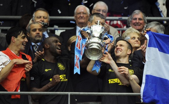 epa03696600 Wigan Athletic&#039;s (L-R) Paul Scharner, Emmerson Boyce and captain Gary Caldwell lift the trophy after winning the English FA Cup final soccer match between Manchester City and Wigan At ...