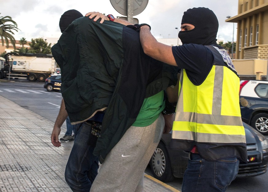 epa05559722 Spanish policemen escort an alleged jihadist arrested during a police operation in Melilla, the Spanish enclave in the North of Africa, 28 September 2016. Five suspected jihadists have bee ...