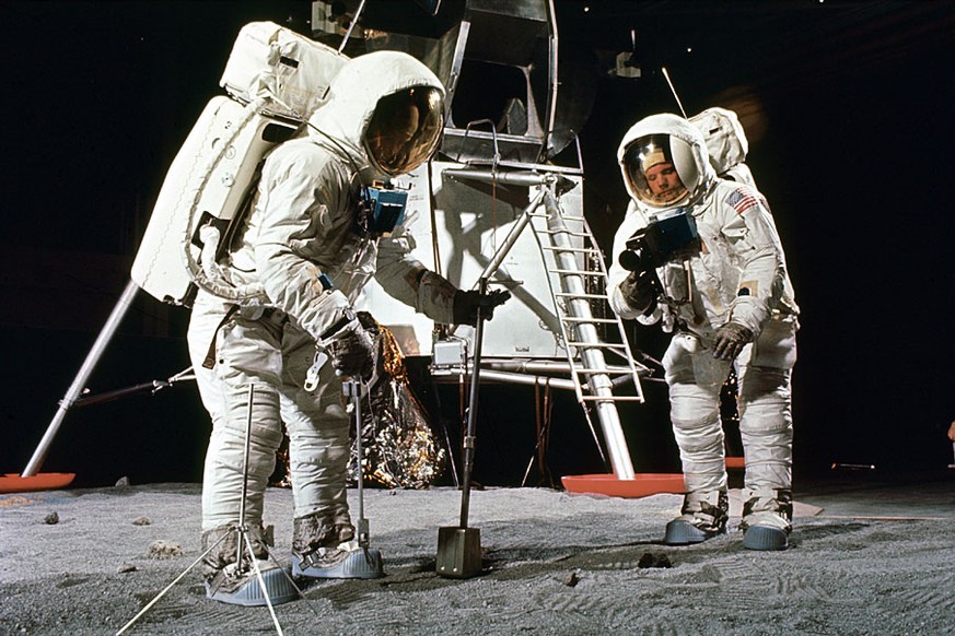 Buzz Aldrin and Neil Armstrong in training for the Apollo 11 mission. Aldrin scoops up a soil sample, while Armstrong aims his camera.