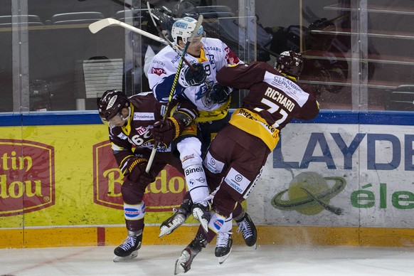 Geneve-Servette&#039;s players forward Noah Rod, left, and center Tanner Richard, right, check Zug&#039;s forward Dario Simion, centre, during a National League regular season game of the Swiss Champi ...