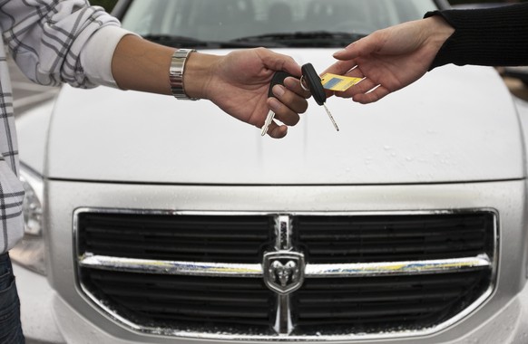 A car salesman hands over a key to a customer at car dealer &quot;Auto Zueri-Oberland&quot;, pictured on August 3, 2009 in Hinwil in the canton of Zurich, Switzerland. In the background a &quot;Dodge& ...