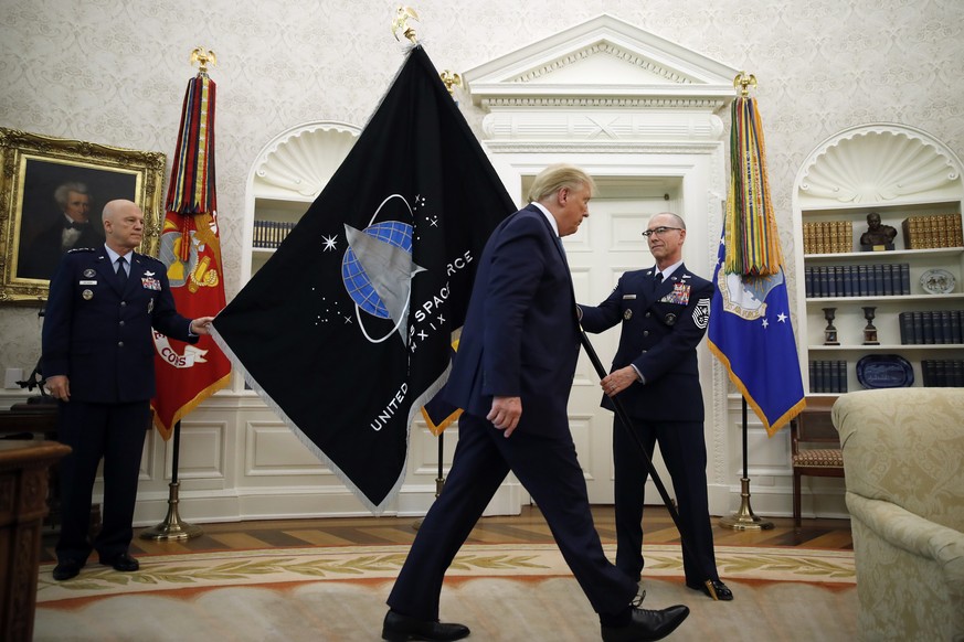 FILE - In this May 15, 2020 file photo, Chief of Space Operations at United States Space Force Gen. John Raymond, left, and Chief Master Sgt. Roger Towberman, right, hold the U.S. Space Force flag