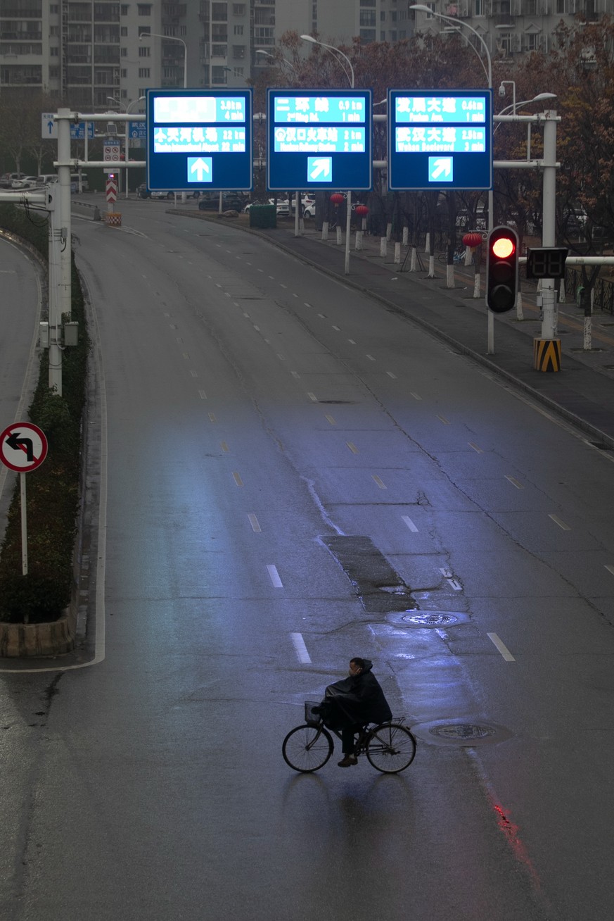 epaselect epa08154528 A cyclist crosses an empty street in Wuhan City, Hubei Province, China, 23 January 2020. The streets of Wuhan are empty after authorities imposed a complete travel ban on residen ...