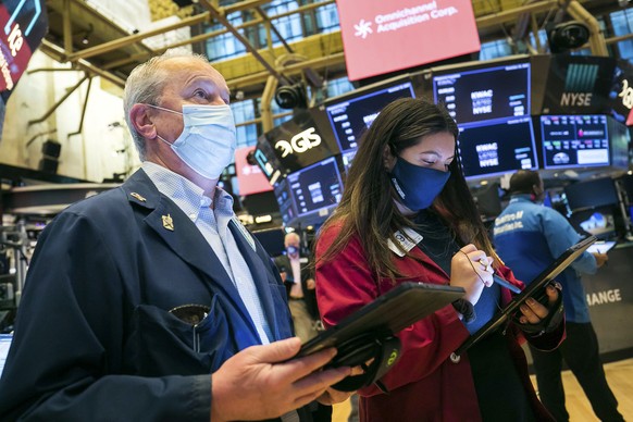 In this photo provided by the New York Stock Exchange, traders James Riley and Ashley Lara work on the floor Friday, Nov. 20, 2020. U.S. stocks are pulling a bit lower in midday trading Friday as worr ...