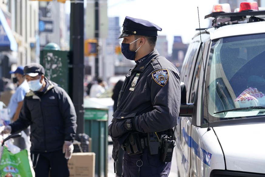 New York City Police Department Officer Rodney Hierro, right, keeps an eye on pedestrians and vendors along a busy section of Main Street in Flushing, a largely Asian American neighborhood, Tuesday, M ...