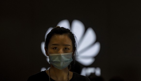 epa08530326 A woman wearing a mask for protection, stands in the Huawei shop in Shanghai, China, 6 July 2020. As reported by media on 4 July, British Prime Minister Boris Johnson is expected to begin  ...