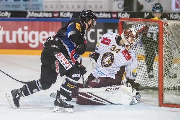 L&#039;attaquant fribourgeois Jim Slater, gauche, marque un but au gardien genevois Gauthier Descloux, droite, lors de la rencontre du championnat suisse de hockey sur glace de National League entre l ...