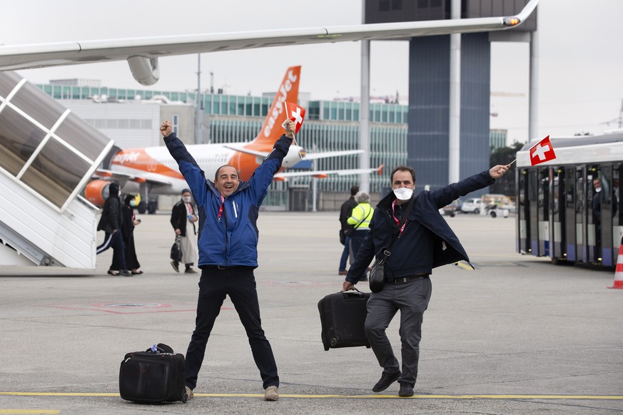 epa08330491 Two passengers wave small Swiss national flags after disembarking from a flight of the Swiss International Air Lines at the Geneve Aeroport, in Geneva, Switzerland, 29 March 2020. The flig ...