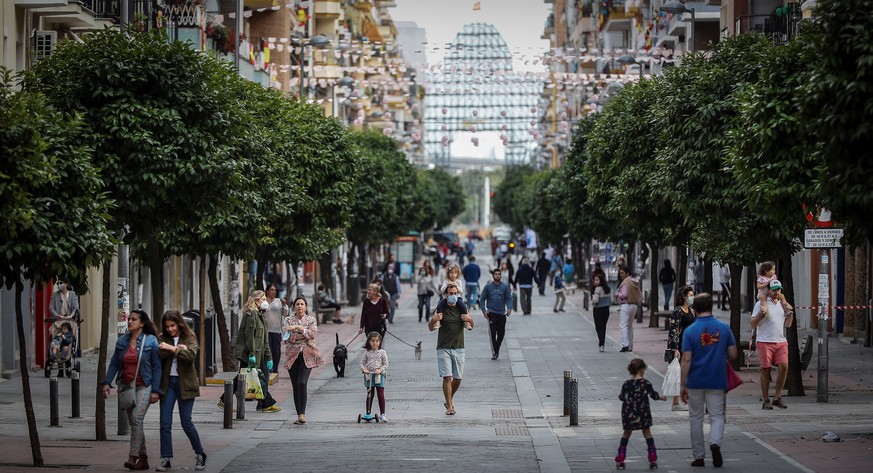 epa08385651 People walk down the San Jacinto street, in Sevilla, Spain, 26 April 2020, on the first day in which minors are allowed an hour a day walk since lockdown was ordered in Spain 43 days ago i ...