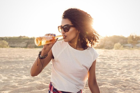 Frau trinkt Bier am Strand