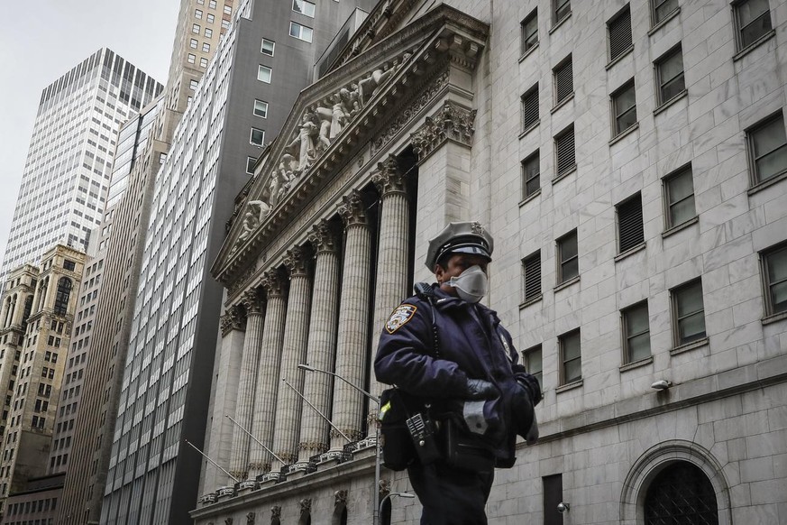 An NYPD officer walks along a sparsely populated Wall Street, Friday, May 1, 2020, in the Manhattan borough of New York. (AP Photo/John Minchillo)