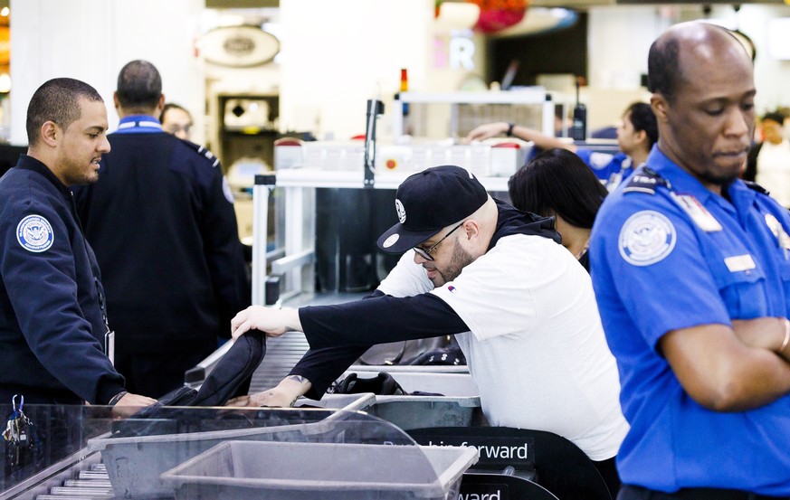 epa08088420 People gather belongings to pass through a security checkpoint at LaGuardia Airport in New York, New York, USA, 23 December 2019. The Transportation Safety Administration (TSA) expects a r ...