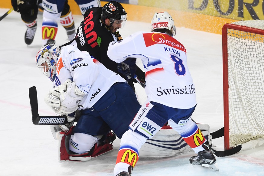 Lugano&#039;s player Maxim Lapierre, left, fight for the puck with Zurich&#039;s goalkeeper Lukas Flüeler, center, and Zurich&#039;s player Kevin Klein, right, during the preliminary round game of Nat ...