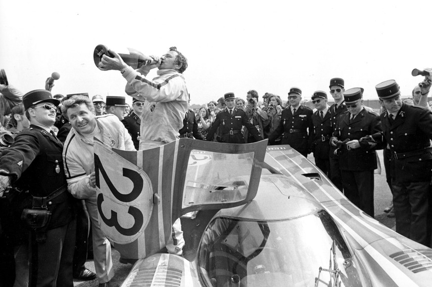Hans Herrmann stands on the floor of the winning Salzburg 917k as he celebrates with champagne after his victory in the 24 Hours Le Mans car race with his teammate Richard Attwood, not shown, in Paris ...