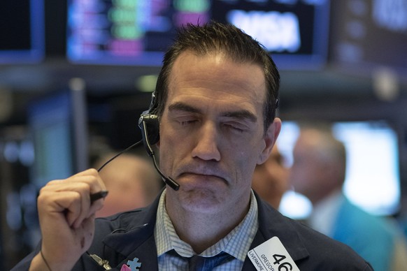Stock trader Gregory Rowe works at the New York Stock Exchange, Wednesday, March 18, 2020 in New York. Global stock markets have sunk in a third day of wild price swings after President Donald Trump p ...