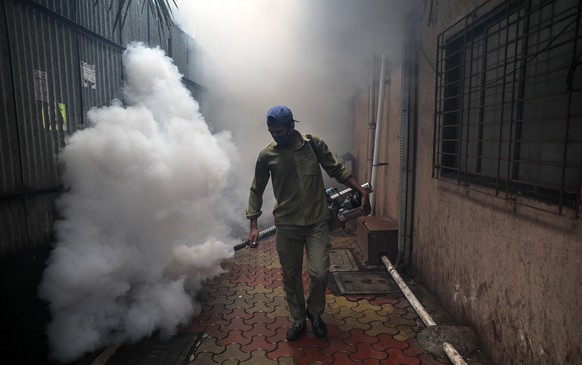 epa08570591 A municipal worker wearing a face mask uses an anti-malaria fumigation spray machine at a residential area in Mumbai, India, 28 July, 2020. The measure is regularly taken by the municipal  ...
