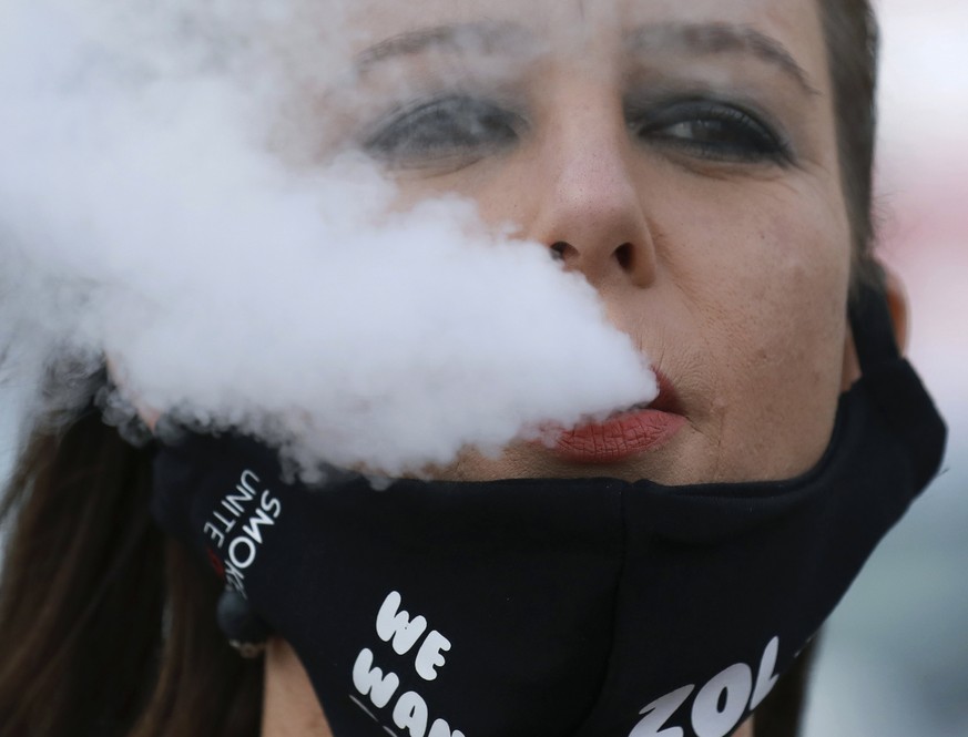 In this June 2, 2020 photo, a demonstrator exhales smoke during a protest against the tobacco ban outside parliament in Cape Town, South Africa. An effort to lift South Africa���s ban on cigarette sal ...