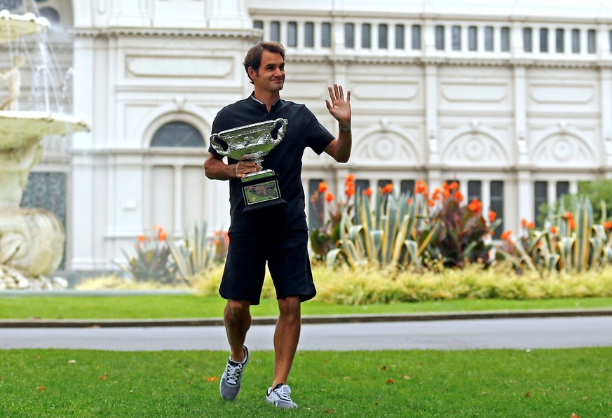 Switzerland&#039;s Roger Federer waves to supporters as he holds the trophy during a photo call the morning after he won the Men&#039;s singles final at the Australian Open tennis tournament in Melbou ...