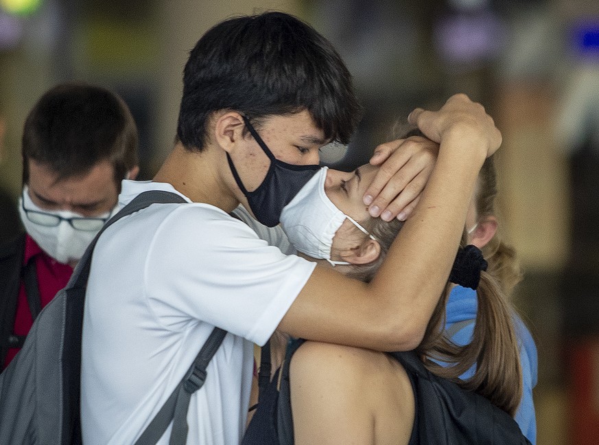 A young couple with face masks kisses goodbye at the airport in Frankfurt, Germany, Monday, Aug. 3, 2020. (AP Photo/Michael Probst)