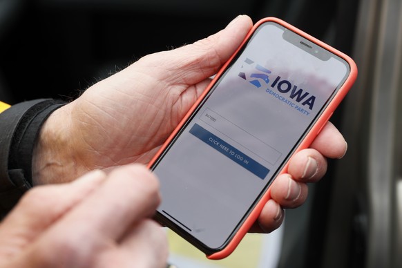 Precinct captain Carl Voss, of Des Moines, Iowa, holds his iPhone that shows the Iowa Democratic Party&#039;s caucus reporting app Tuesday, Feb. 4, 2020, in Des Moines, Iowa. (AP Photo/Charlie Neiberg ...