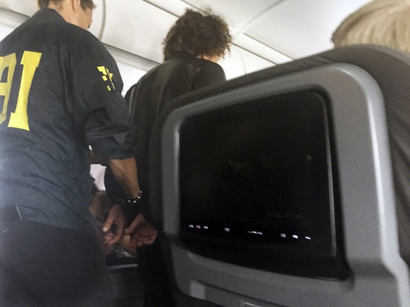 FILE- In this file photo provided by Donna Basden, a man is escorted off an American Airlines flight after it landed in Honolulu, Friday, May 19, 2017. Court records say the man who caused a disturban ...