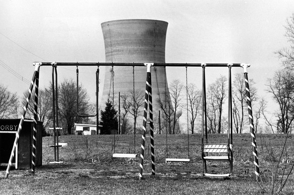 A cooling tower of the Three Mile Island nuclear power plant near Harrisburg, Pa., looms behind an abandoned playground, March 30, 1979. (AP Photo/Barry Thumma)