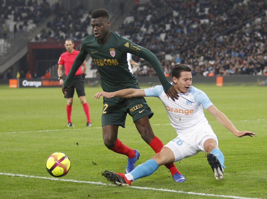 Monaco defender Benoit Badiashile Mukinayi, left, challenges for the ball with Marseille&#039;s Florian Thauvin during the League One soccer match between Marseille and Monaco at the Velodrome stadium ...