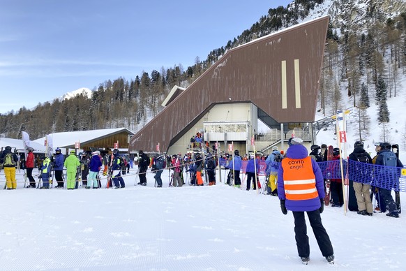 A ski lift staff identified as &quot;Covid Angel&quot; looking at skiers and snowboarders line up in a queue at the start of a ski lift during the coronavirus disease (COVID-19) outbreak, in the Alpin ...