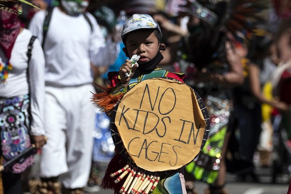 epa08542775 A young protester wearing traditional outfit holds a sign reading &#039;No Kids in Cages&#039; as protesters of the Latino and indigenous community walk to take part in the Black and Brown ...
