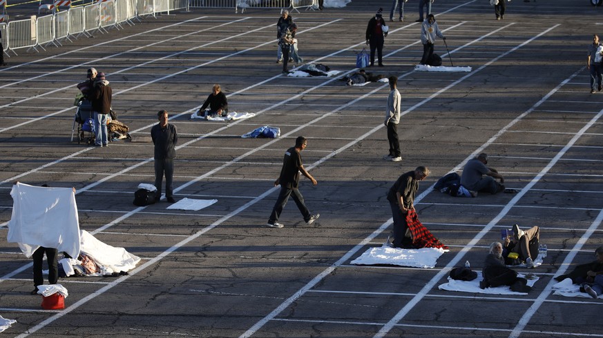 People prepare to sleep in areas marked by painted boxes on the ground of a parking lot at a makeshift camp for the homeless Monday, March 30, 2020, in Las Vegas. Officials opened part of the ot as a  ...