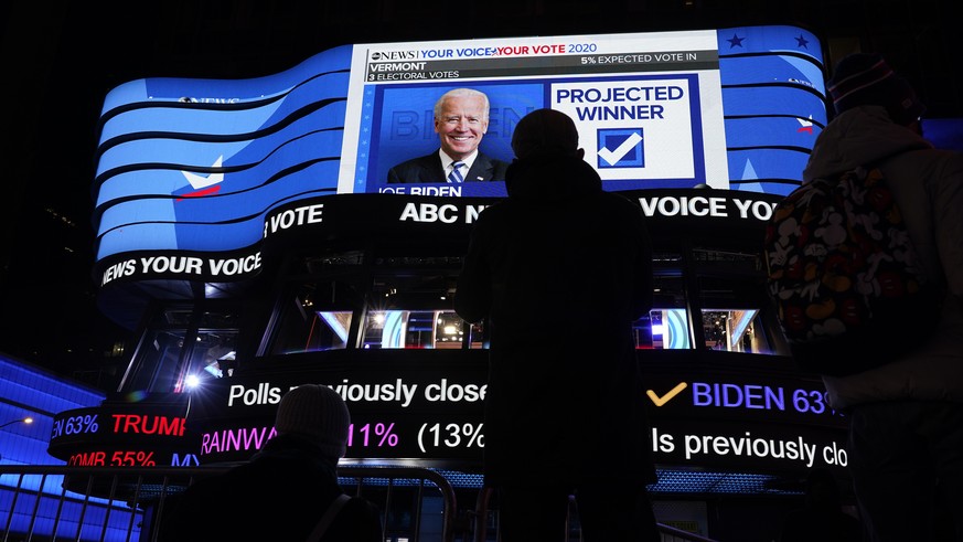 Pedestrians stop to watch election results on the electronic billboards in Times Square, Tuesday, Nov. 3, 2020, in New York. (AP Photo/Seth Wenig)