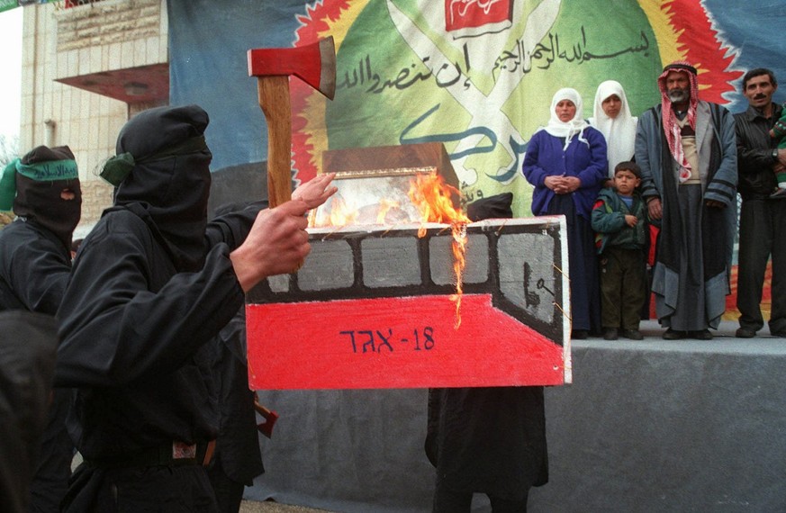 Masked members of the Islamic militant group Hamas burn an effigy of a number eighteen Israeli bus during a demonstration held at Hebron&#039;s Polytechnic College Monday Jan. 5, 1998. The demonstrati ...