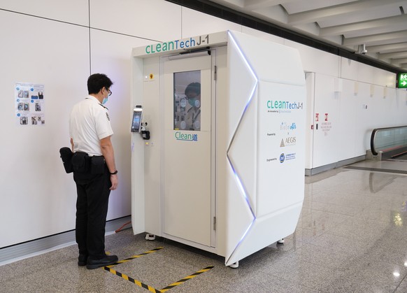 epa08387107 A handout photograph provided by Hong Kong International Airport shows a worker going through CLeanTech, a full-body disinfection channel facility, at Hong Kong International Airport in Ho ...