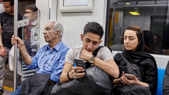 Ein junges iranisches Pärchen schaut sich Inhalte auf einem Smartphone an.