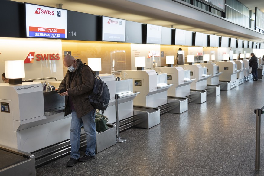 epa09091916 Passenger wearing a face mask waits for check-in at the counter of the Swiss International Air Lines at the Zuerich Airport (Flughafen Zuerich) amid the coronavirus disease (COVID-19) outb ...