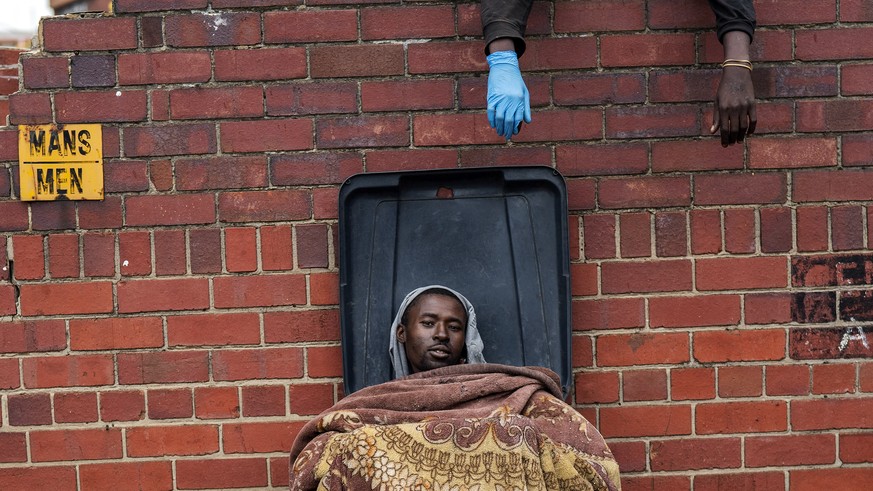 Henry sits in a bin as he and other homeless people rest at the Caledonian stadium downtown Pretoria, South Africa, Thursday April 2, 2020, after being rounded up by police in an effort to enforce a 2 ...