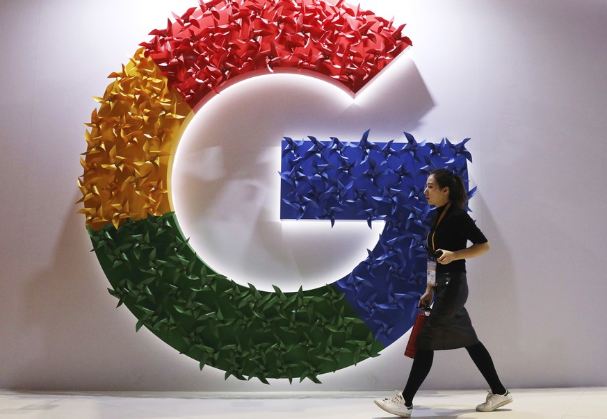 FILE - In this Monday, Nov. 5, 2018, file photo, a woman walks past the logo for Google at the China International Import Expo in Shanghai. Chinese tech giant Huawei is racing to develop replacements  ...