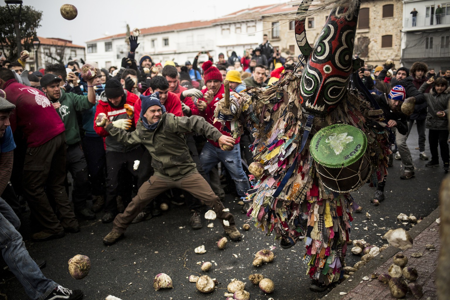 In this Saturday, Jan. 19, 2019 photo, people throw turnips at the Jarramplas as he makes his way through the streets beating his drum during the Jarramplas festival in the tiny southwestern Spanish t ...