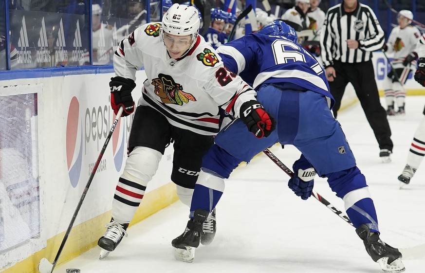 Chicago Blackhawks center Philipp Kurashev (23) slips between Tampa Bay Lightning center Mitchell Stephens (67) and the dasher during the first period of an NHL hockey game Friday, Jan. 15, 2021, in T ...