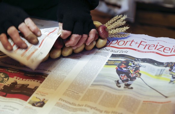 Eine Verkaeuferin packt Zwiebeln in eine alte Ausgabe der Berner Zeitung, waehrend dem traditionellen &quot;Zibelemaerit&quot; am Montag, 23. November 2015 in Bern. Der Zibelemaerit findet am vierten  ...