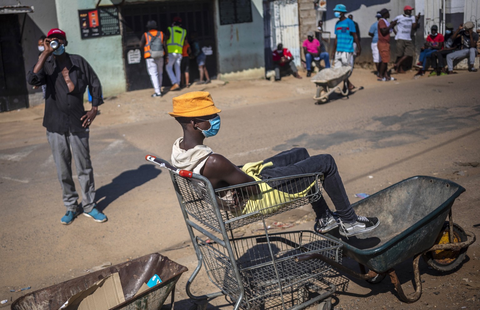 epa08402587 Wheel barrow couriers sits in their wheel barrows waiting to take food from a food hand out school to their customers in nearby shanty town on day 40 of the national lockdown as a result o ...