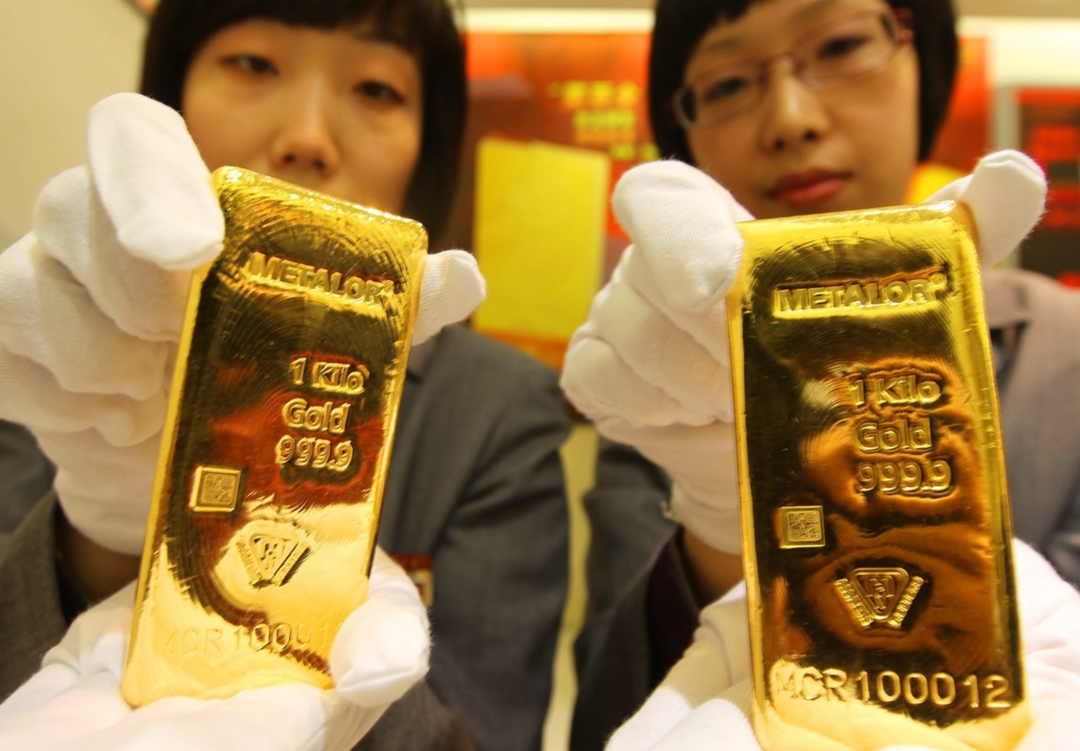 epa02091575 A photograph made available on 25 March 2010 showing two salesgirls show the one kilo Metalor gold bullions made by Swiss company Metalor on the first day of trading in Beijing 24 March 20 ...