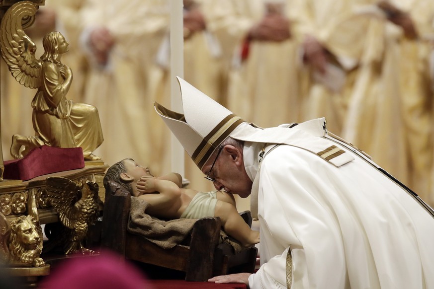 Pope Francis kisses a statue of Baby Jesus as he celebrates the Christmas Eve Mass in St. Peter&#039;s Basilica at the Vatican, Monday, Dec. 24, 2018. (AP Photo/Alessandra Tarantino)
