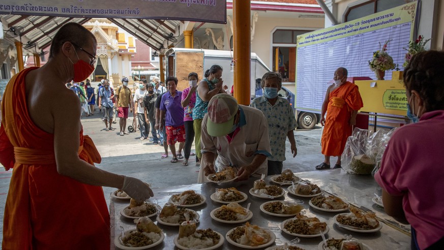 People stand spread out in line for free meals tat the Wat Arun Buddhist temple in Bangkok, Thailand, Tuesday, March 31, 2020. The Wat Arun temple provides two free meals a day for people in need whos ...